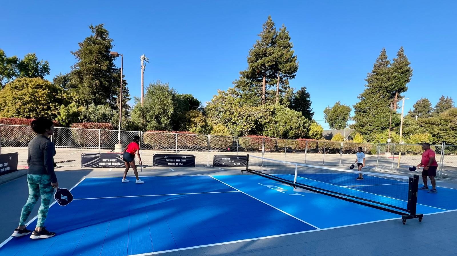 Players rallying on a Jolt-branded outdoor pickleball court
